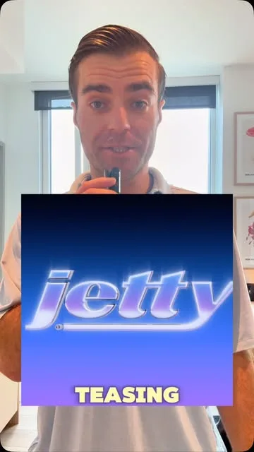 Jonathan holding a microphone behind a blue Jetty graphic with the word Teasing