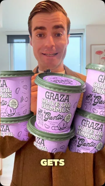 Jonathan behind purple tubs of Graza garlic olive oil hummus with green lids