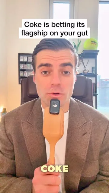 Jonathan holding a wooden spatula with a microphone beneath text about Coke betting its flagship on gut health